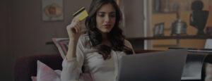 Woman holding a credit card in front of her laptop computer